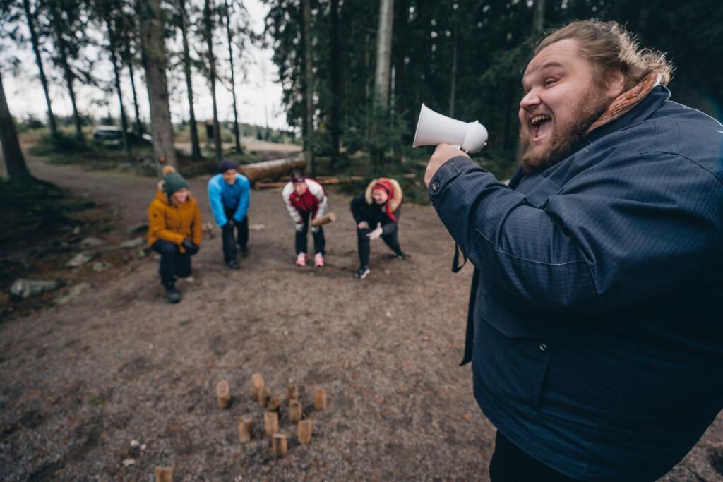 Kuvassa etualalla mies huutaa megafoniin ja taustalla näkyy neljä muuta henkilöä.